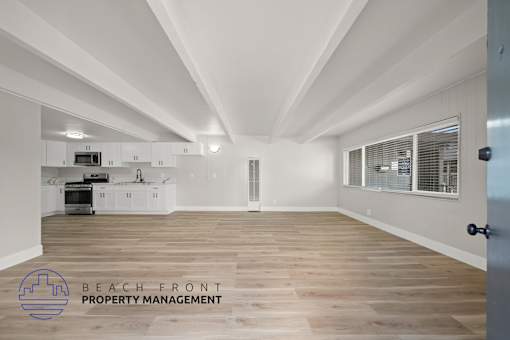 A spacious kitchen with wooden floors and white walls.