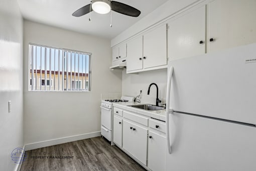 A white kitchen with a fan on the ceiling.
