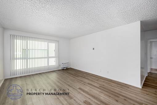 A room with wooden flooring and a window with blinds.