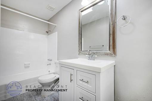 A white bathroom with a toilet, sink, and mirror.