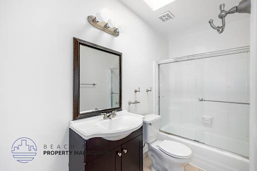 A bathroom with a sink, mirror, toilet and bathtub.