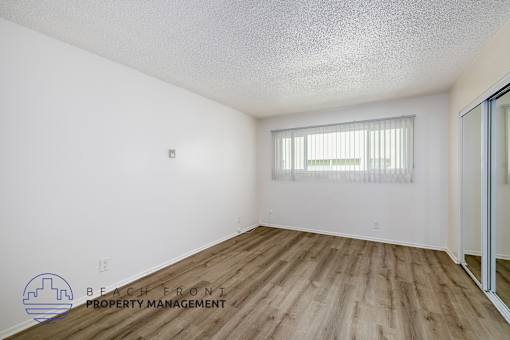 A room with wooden flooring and a window with blinds.