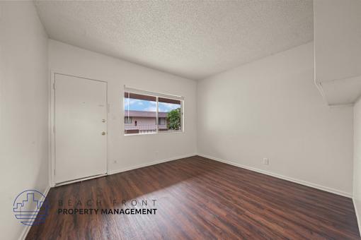 A room with wooden floors and a window showing a view of a house.