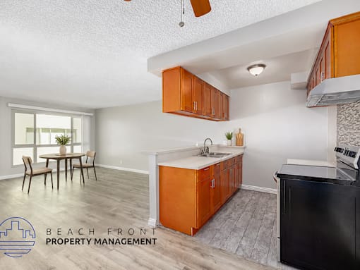 A kitchen with orange cabinets and a black fridge is shown.