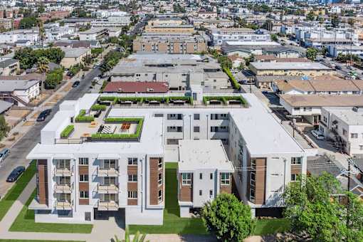 A large white building with a green roof is surrounded by smaller buildings.