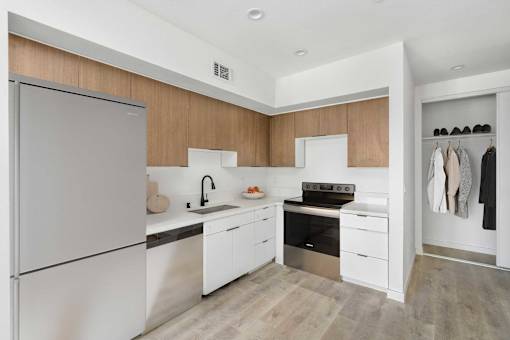 A modern kitchen with a refrigerator, sink, stove, and cabinets.