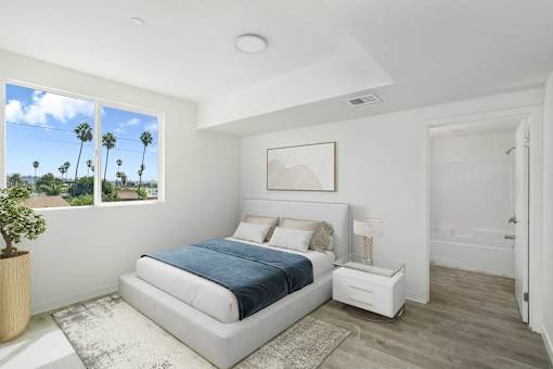 A bedroom with a large bed and a view of palm trees outside the window.