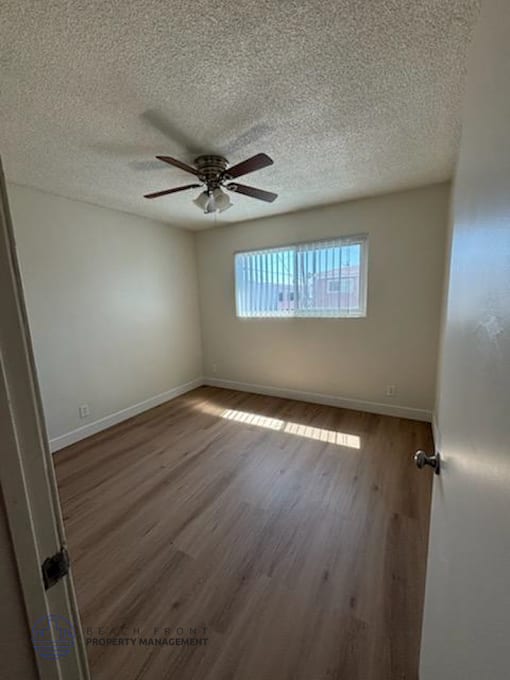 A room with a ceiling fan and wooden flooring.