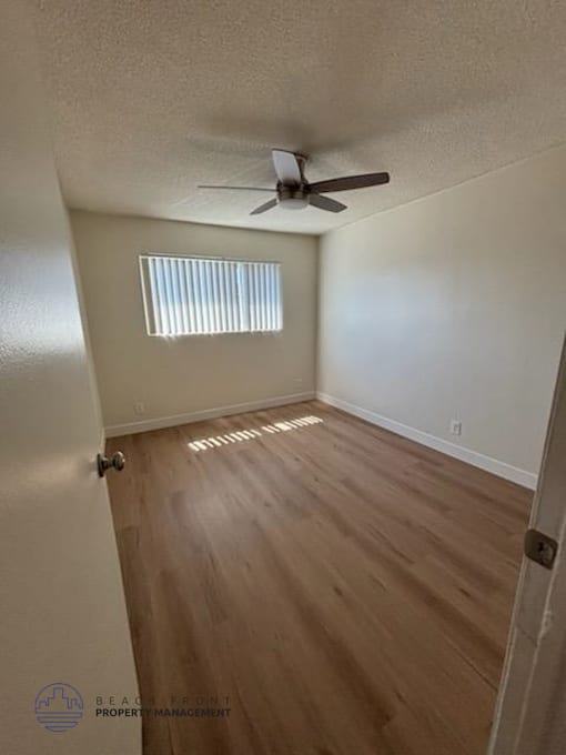 A room with a ceiling fan and wooden flooring.
