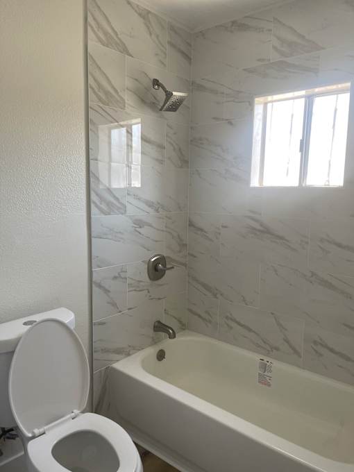 a white bathroom with a toilet and a tub and a window