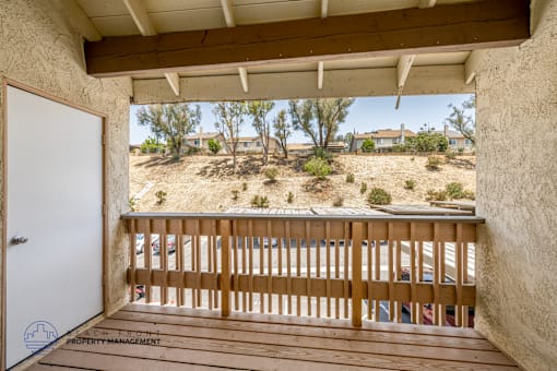 A spacious room with wooden flooring and a large window overlooking a beach.