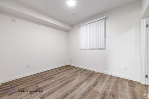 A room with wooden flooring and a window with blinds.