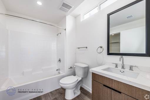 A white bathroom with a toilet, sink, and mirror.
