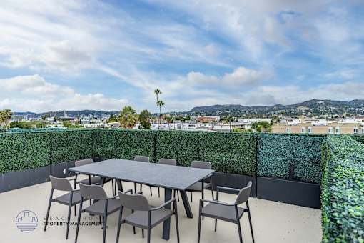 A table with chairs on a patio with a view of the city.