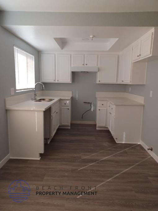an empty kitchen with white cabinets and a sink