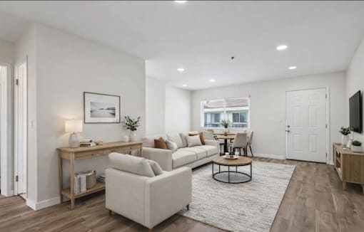 A living room with a white couch, a coffee table, and a television.