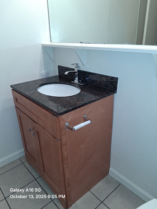 A brown cabinet with a black counter top and a white sink.