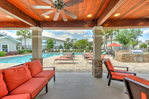 A patio with a red couch and a ceiling fan.