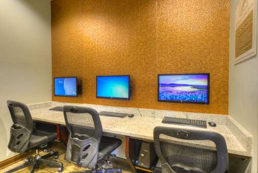 A conference room with a table, chairs, and three monitors.