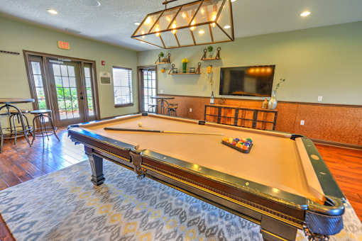 A pool table in a room with a bar and a television.