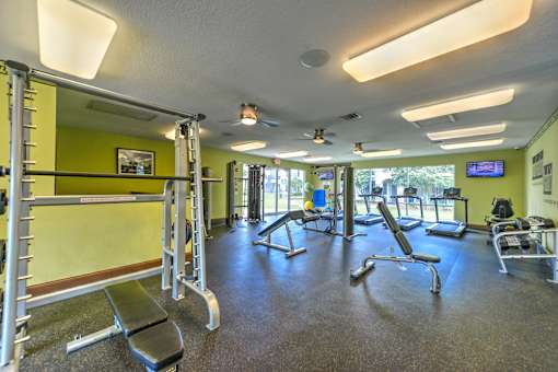 A gym with a variety of equipment including a squat rack, bench, and weights.