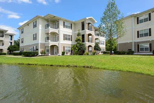 A large apartment complex with a pond in front.