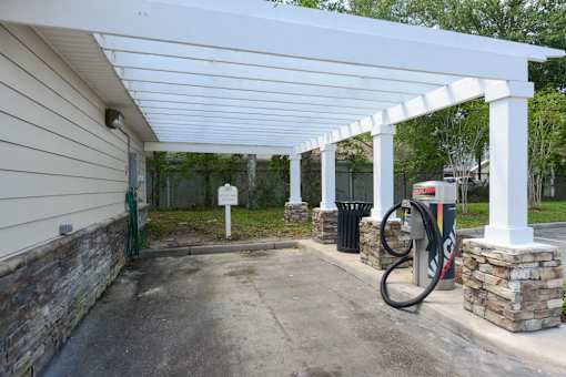 A gas station with a white canopy and a green hose.