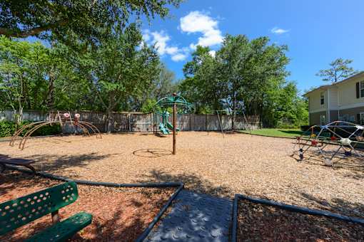 A playground with a green bench and a slide.
