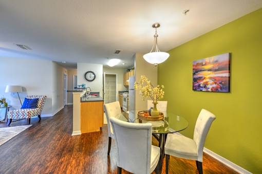 A dining room with a table set for two and a painting on the wall.