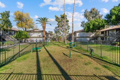 a grassy area with a swing set and a bench in front of a fence