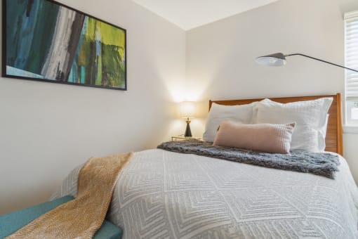 a bedroom with a bed and a lamp and a painting on the wall