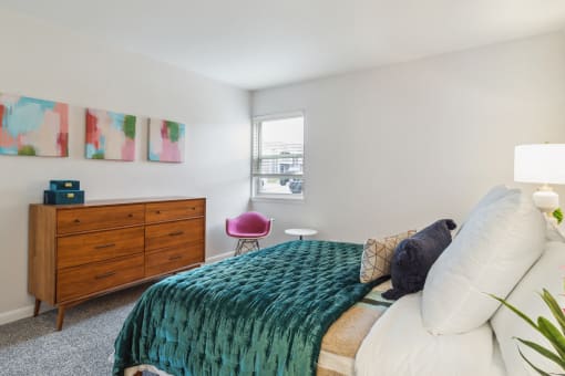 a bedroom with a bed and a dresser and a window
