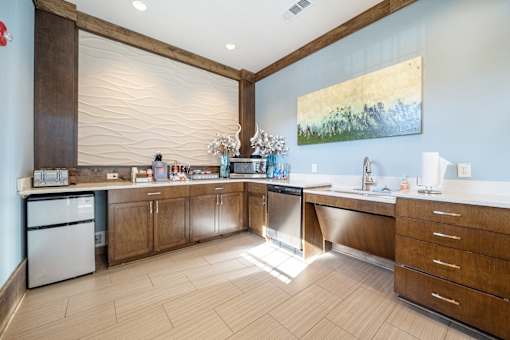 A kitchen with wooden cabinets and a large painting on the wall.