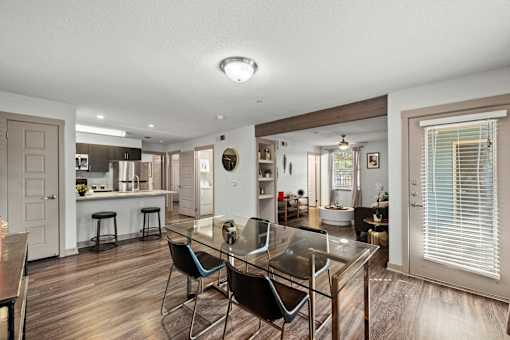 A modern kitchen with a glass table and bar stools.