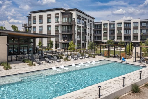 a swimming pool with chaise lounge chairs and a building in the background