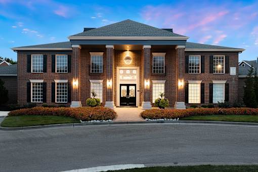 A large, well-lit house with a front yard and a driveway.
