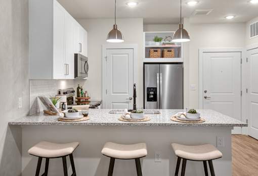 A kitchen with a white countertop and stools.