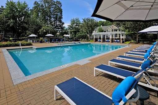 A pool with blue chairs and a white umbrella.