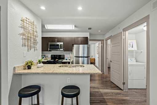 A kitchen with a granite countertop and a bar stool.