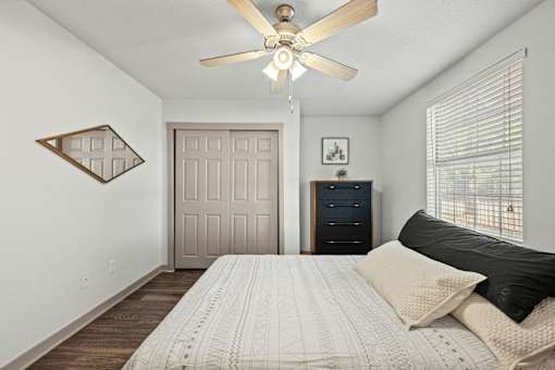 A bedroom with a bed, dresser, and ceiling fan.