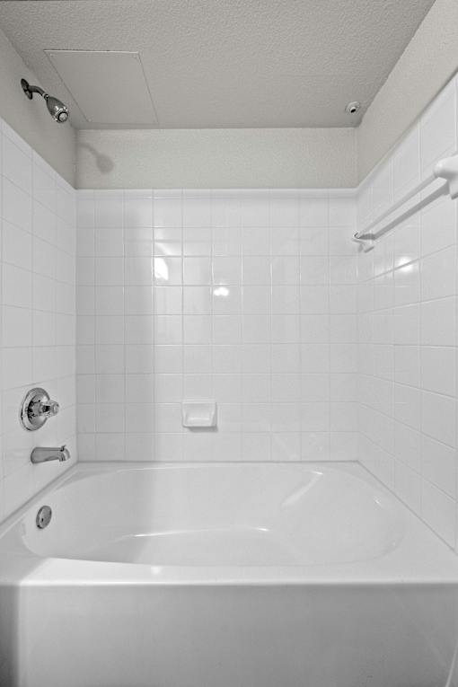 A white bathroom with a white tub and white tiles.