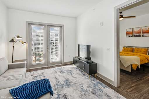A living room with a television, a couch, and a rug.