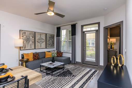 A modern living room with a grey sofa, a coffee table, and a ceiling fan.