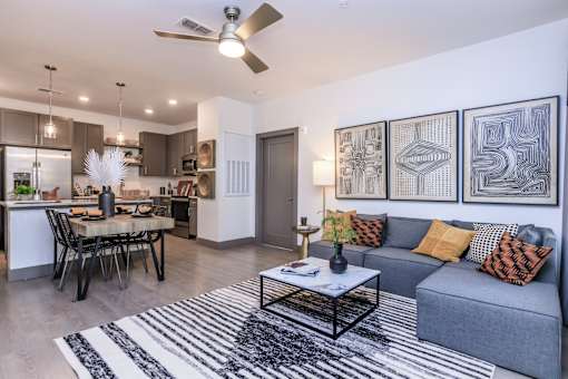A modern living room with a grey couch and a black and white rug.