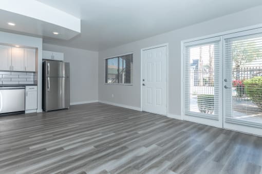 an empty living room with a stainless steel refrigerator and