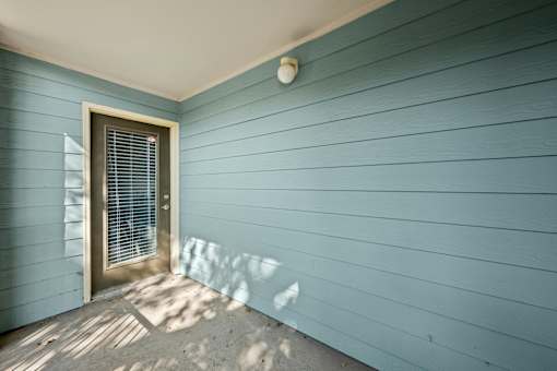 A small door with a window is on the left side of a blue wall.