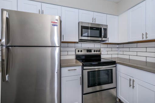 an empty kitchen with stainless steel appliances and white cabinets