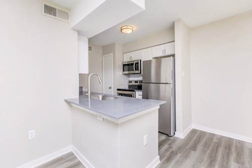 A kitchen with a refrigerator, microwave, and oven.