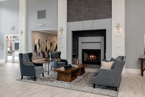 A living room with a fireplace and grey chairs.