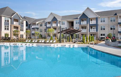 A large swimming pool in front of apartment buildings.